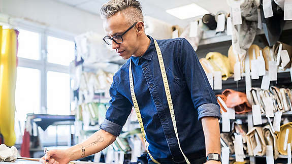 Person working at sewing table with tape measure.