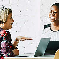 Coworkers at standing desk talking.