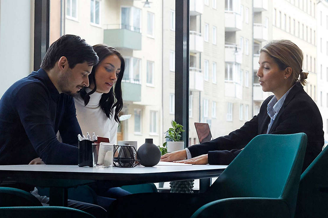 Couple talking to agent while sitting at desk.