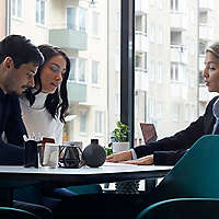 Couple talking to agent while sitting at desk.