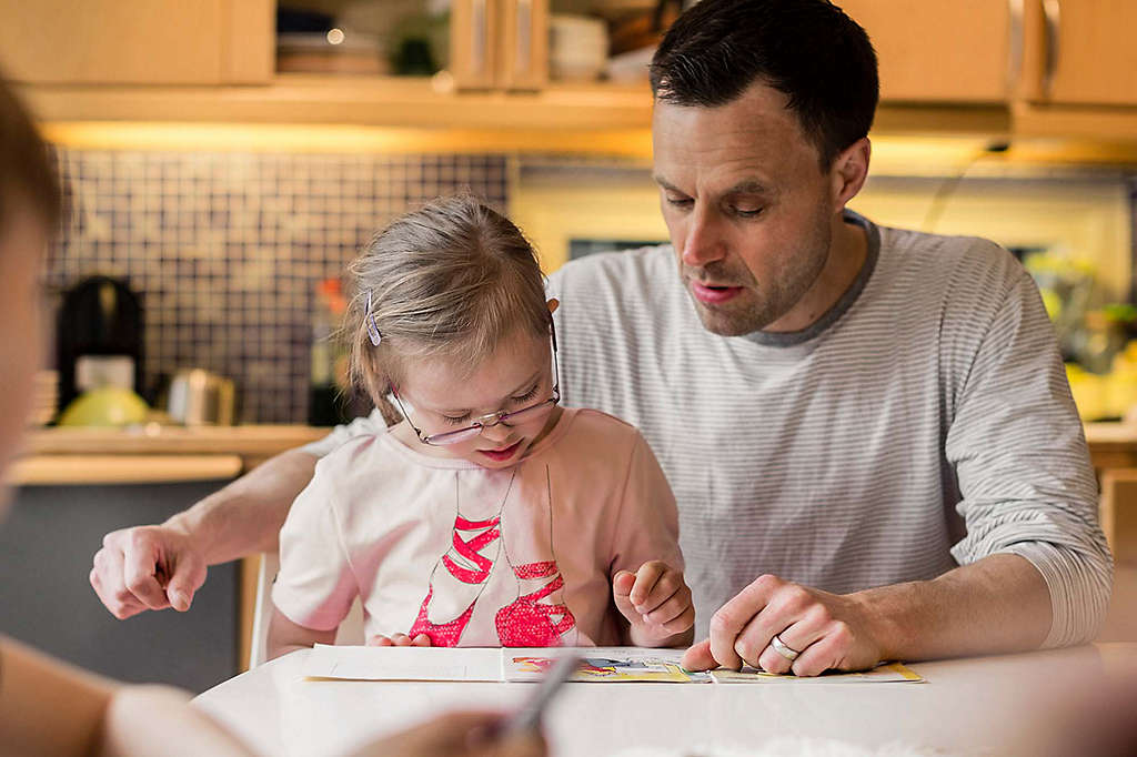 Father playing with daughter at table.