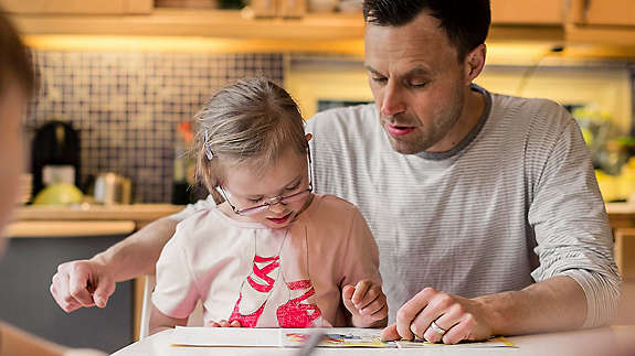 Man sitting with children reading a book 