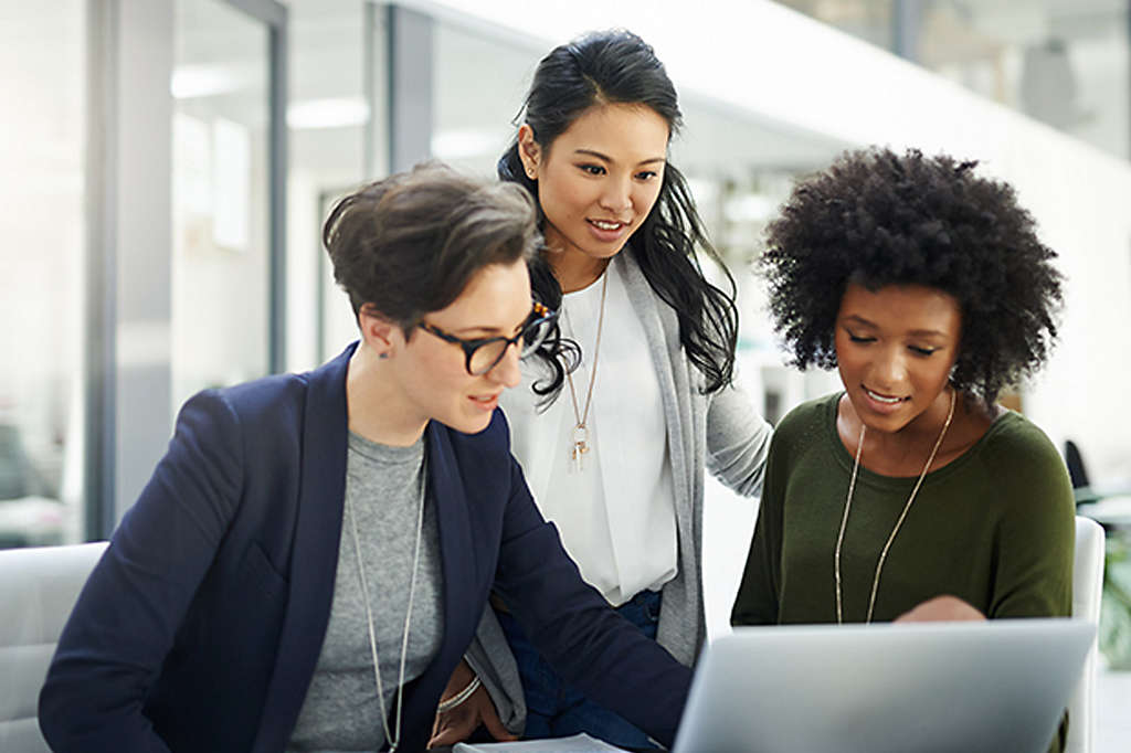 A group of women in an office looking at a laptop and researching 401(k)s