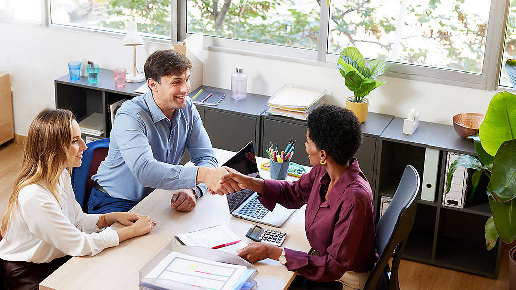 Couple shaking hands with their financial advisor in an office setting