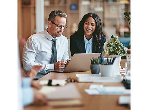 two-smiling-diverse-businesspeople-using-a-laptop-together-at-work