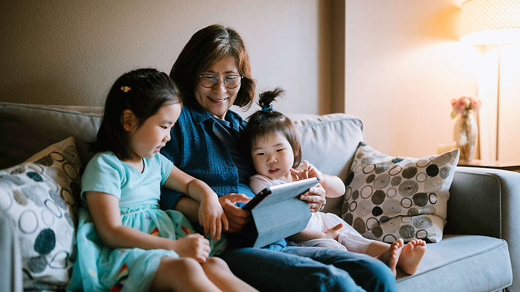 A loving Korean family cuddles together on a living room couch