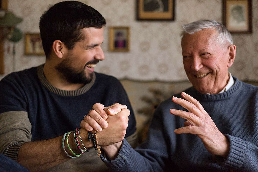 Laughing man holding hands with his smiling grandfather 