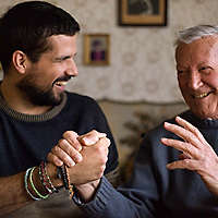 Laughing man holding hands with his smiling grandfather