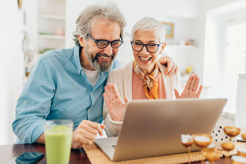 Couple smiling while looking at laptop in kitchen