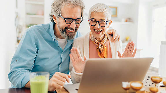 Couple smiling while looking at laptop in kitchen