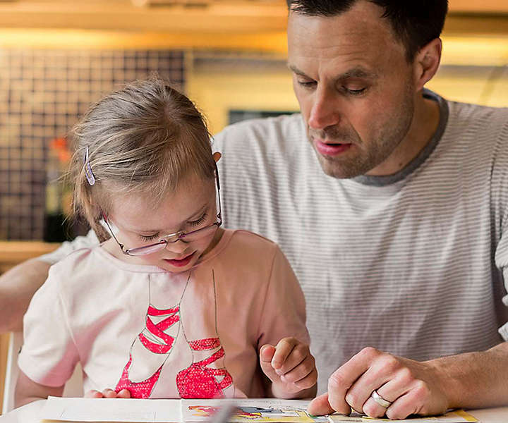 A father and young daughter reading together