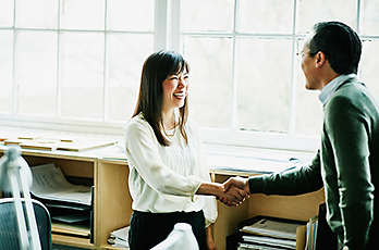 A woman shaking a coworkers hand.