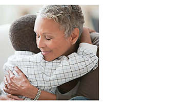 Grandparent bending down to hug grandchild.