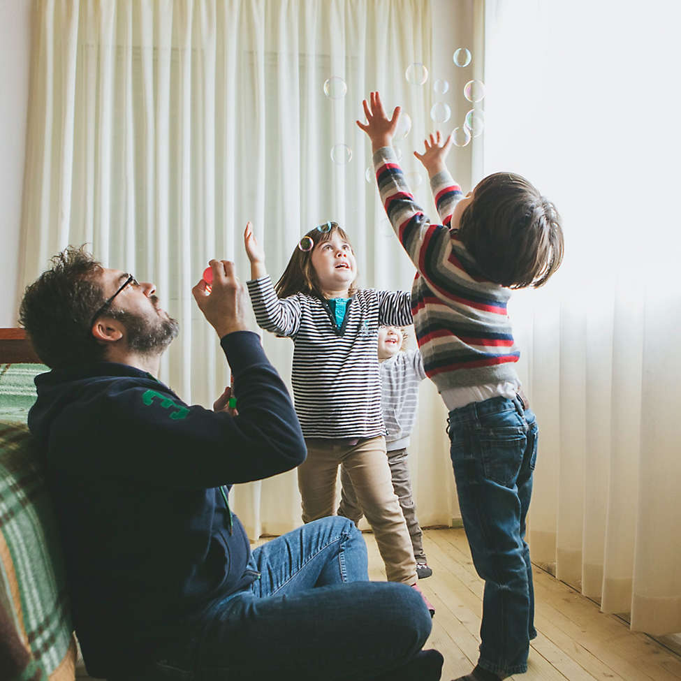 Father blowing bubbles with kids