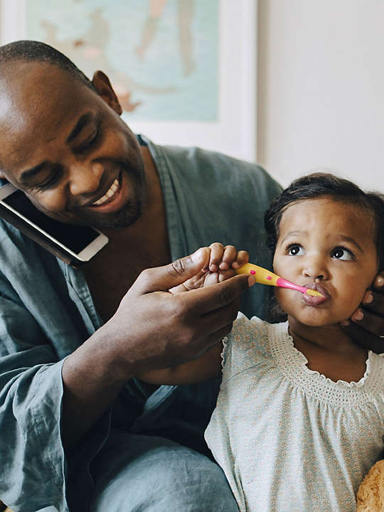 Dad brushing daughters teeth