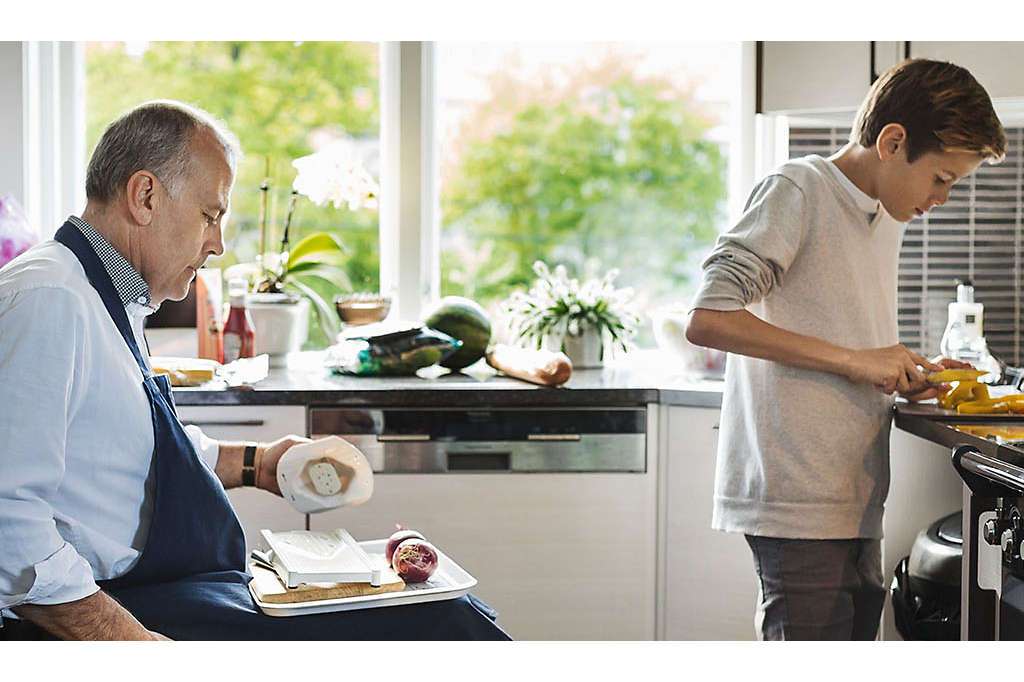 Middle-aged gentleman and son cooking together in kitchen