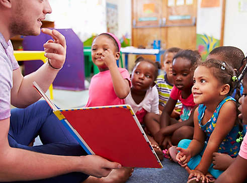 Teacher reading on floor to young students