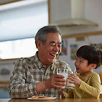 Grandfather and Grandson drinking milk together in their kitchen.