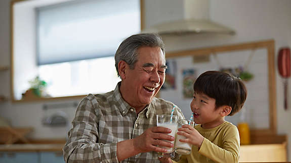 Grandfather and Grandson drinking milk together in their kitchen.