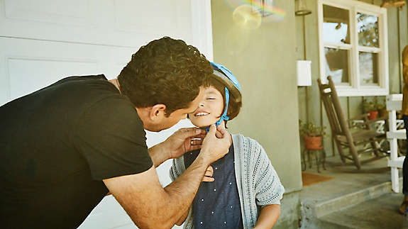 Father putting a bike helmet on his child.