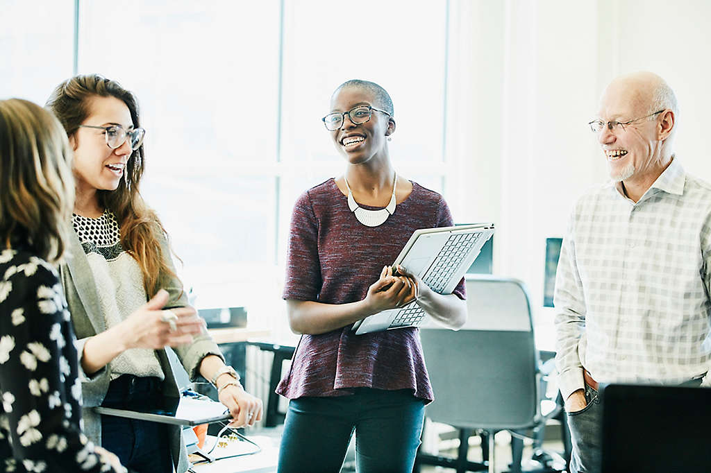 A group of people happily chatting at work.