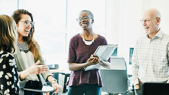 A group of people happily chatting at work.