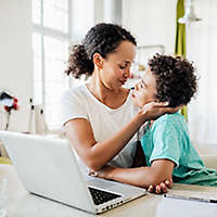 A mother sitting a table lovingly embracing her young son.