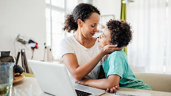 A mother sitting a table lovingly embracing her young son.