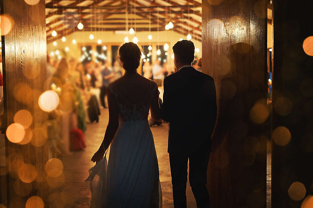 A newly married couple walking into their reception.