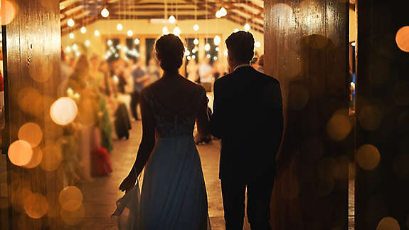 A newly married couple walking into their reception.