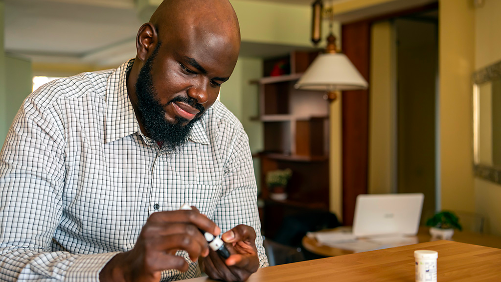 African businessman doing blood dugar test at home