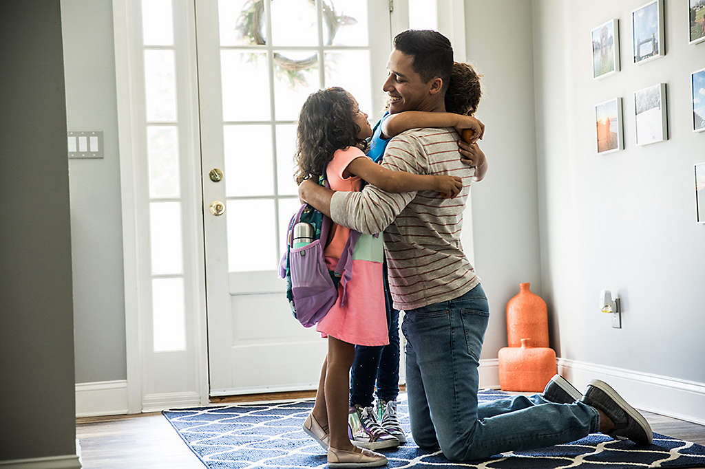 Father hugging his kids after they got home from school