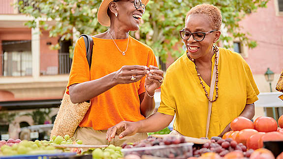 Two women at a farmers market buyingfruits
