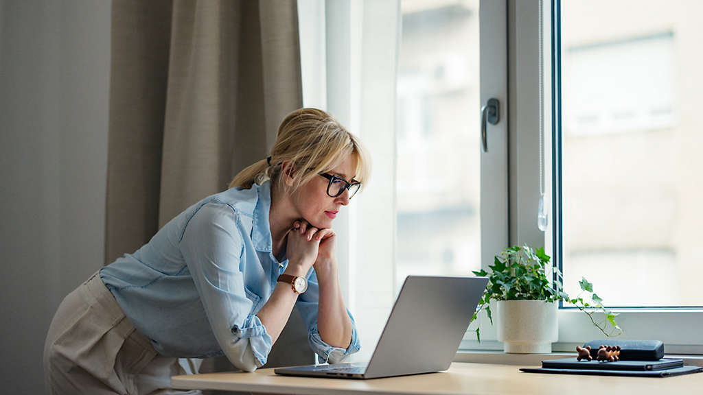 Person sitting at desk looking at bills with a serious expression on their face