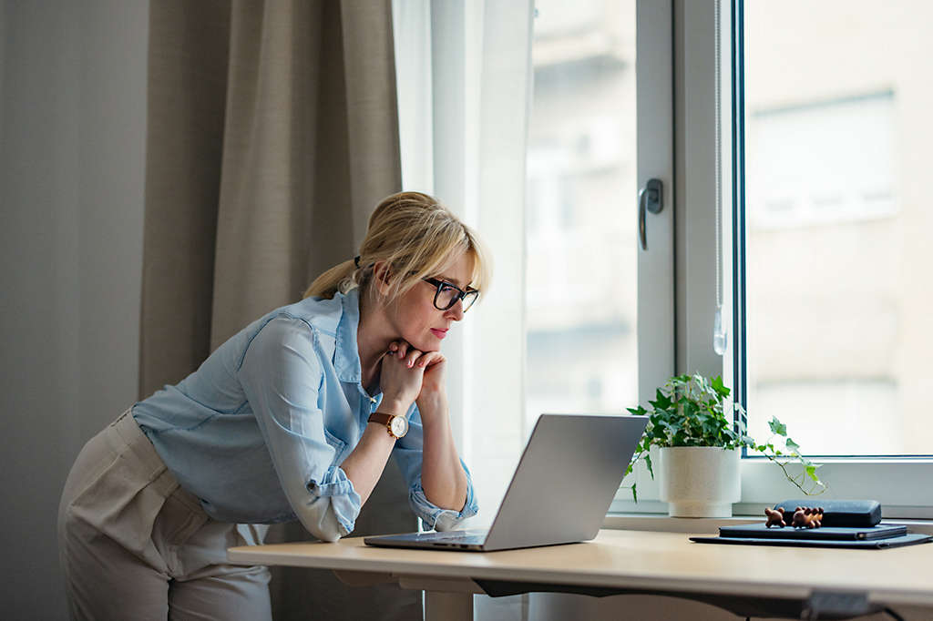 Person sitting at desk looking at bills with a serious expression on their face