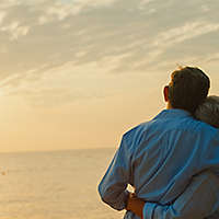 Older couple looking at sunset and embracing
