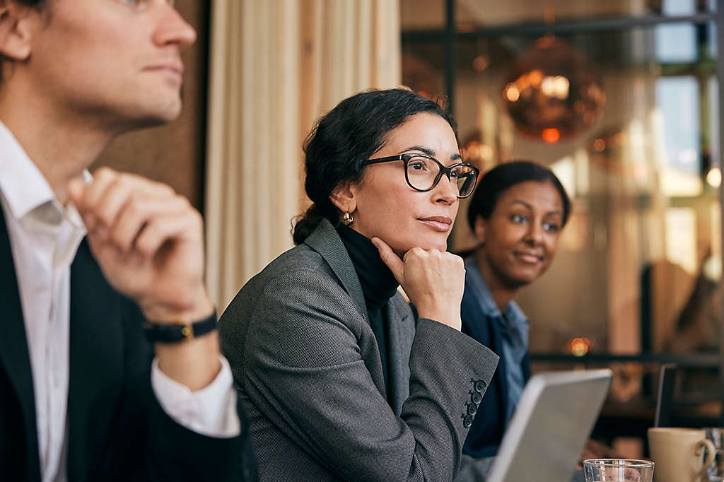 Focused female financial advisor leaning on elbow sitting in meeting at board room