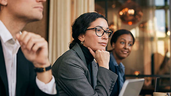 Focused female financial advisor leaning on elbow sitting in meeting at board room