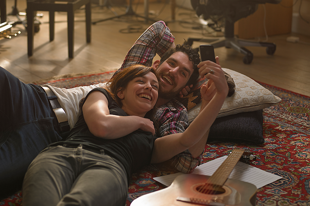 Couple lying on rug taking selfie