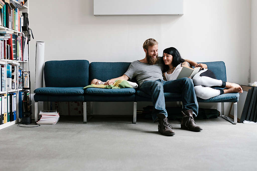 A couple sitting on the couch with their new baby.