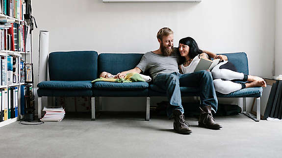 A couple sitting on the couch with their new baby.