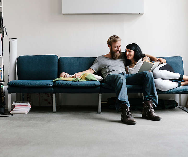 A couple sitting on the couch with their new baby.