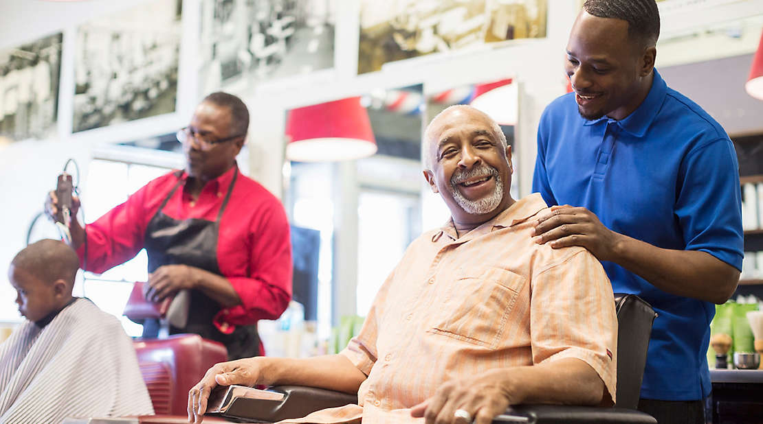 Two men taking care of customers in a barbershop.