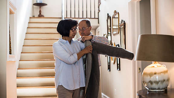 Husband helping his wife put on a jacket.