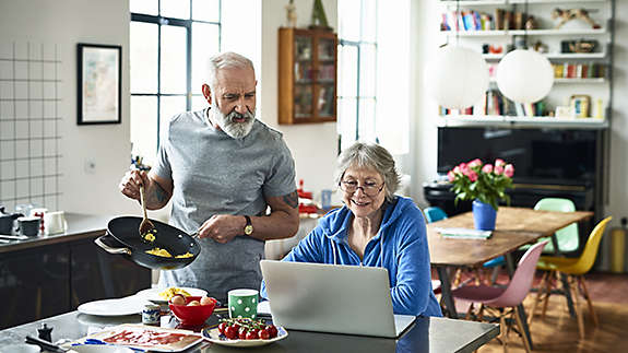 Older, retired couple cooking together in their kitchen