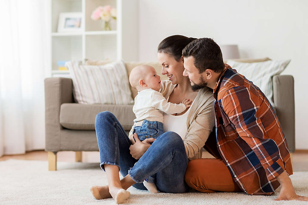  Parents smiling and holding their baby