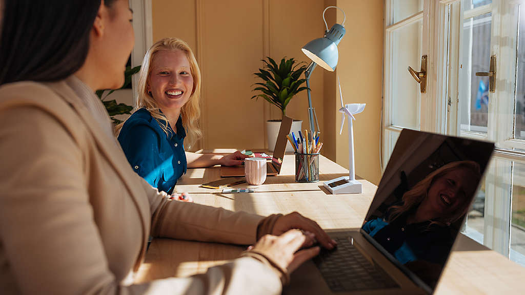 Two younger people working side by side at a well-lit desk
