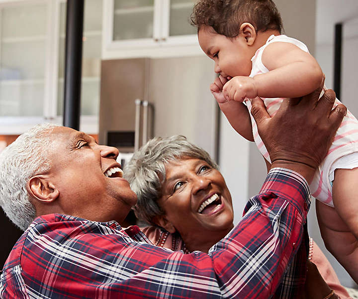 Smiling grandparents holding baby grandchild