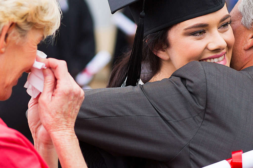 Parents hugging daughter at graduation ceremony