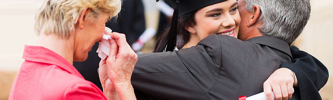 Parents hugging daughter at graduation ceremony